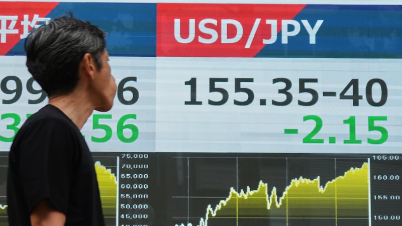 Un hombre pasa junto a un panel electrónico que muestra el tipo de cambio entre el dólar...