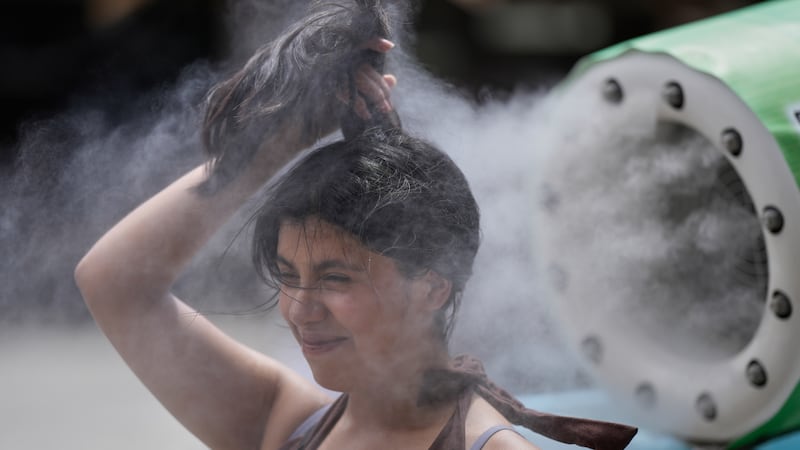 Una persona se refresca en una unidad de enfriamiento durante un caluroso día en el templo...