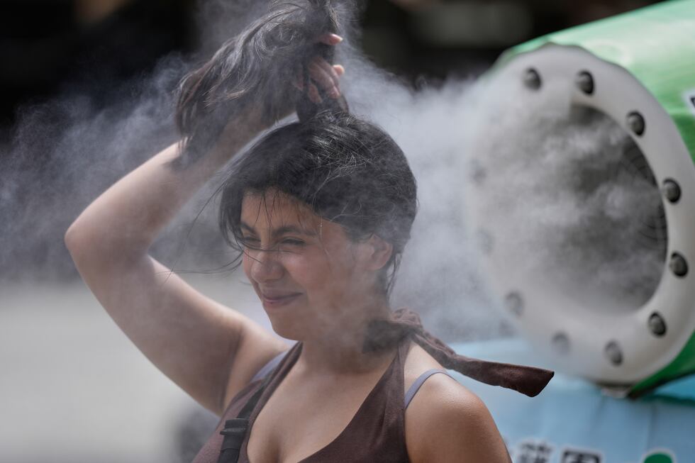 Una persona se refresca en una unidad de enfriamiento durante un caluroso día en el templo...