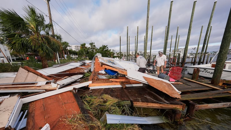 People retrieve belongings from a collapsed boat house in the aftermath of Hurricane Isaias in...