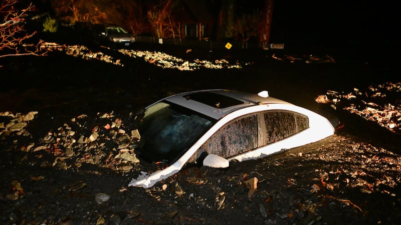 Un auto se ve enterrado en lodo tras una inundación el miércoles 24 de diciembre en...