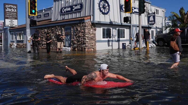 Un hombre surfea en una inundación, el miércoles 28 de octubre de 2026, en Huntington Beach,...