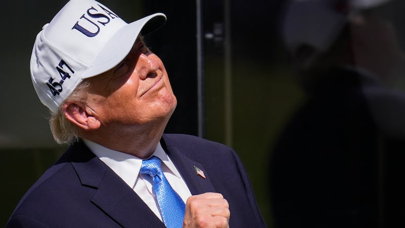 El presidente Donald Trump levanta el puño en el primer tee antes de los partidos individuales...