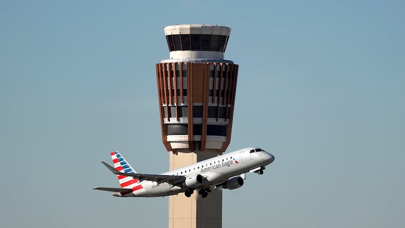Un avión American Eagle de American Airlines pasa por la torre de control de tráfico aéreo en...