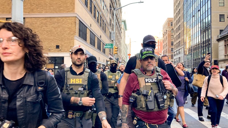 Agentes federales caminan por Lafayette Street seguidos por manifestantes tras una redada de...